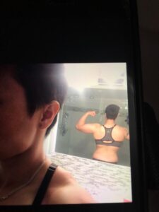 A photograph of a woman's muscular back taken in a mirror. 